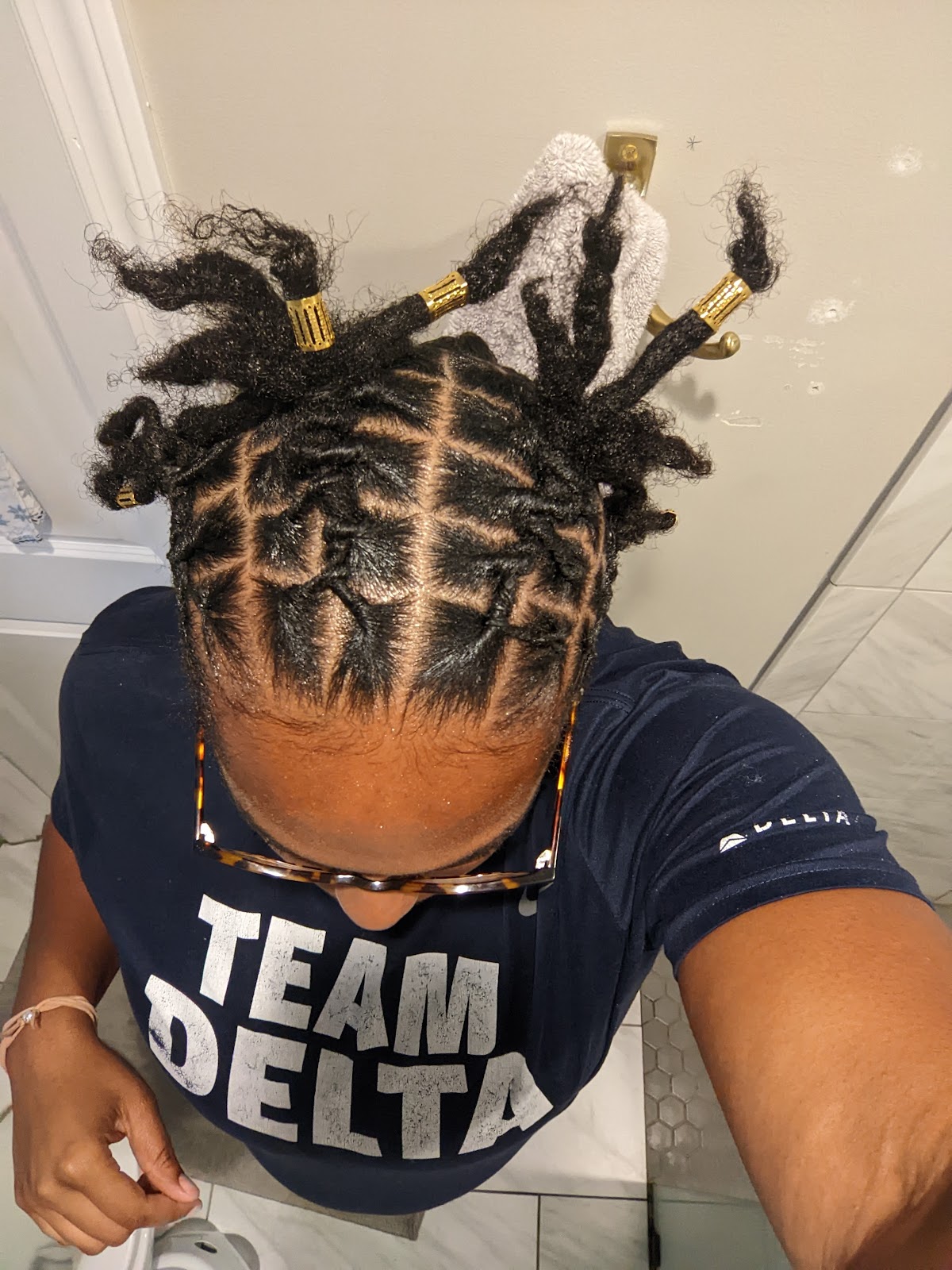 Crisp loc retwist with a clean grid parting and gold loc jewelry